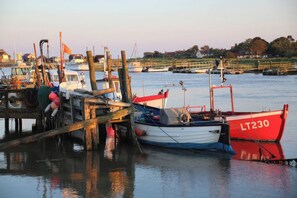 A harbor with boats docked, wooden structures, and a calm water body. - No 1 The Martins (Reydon)