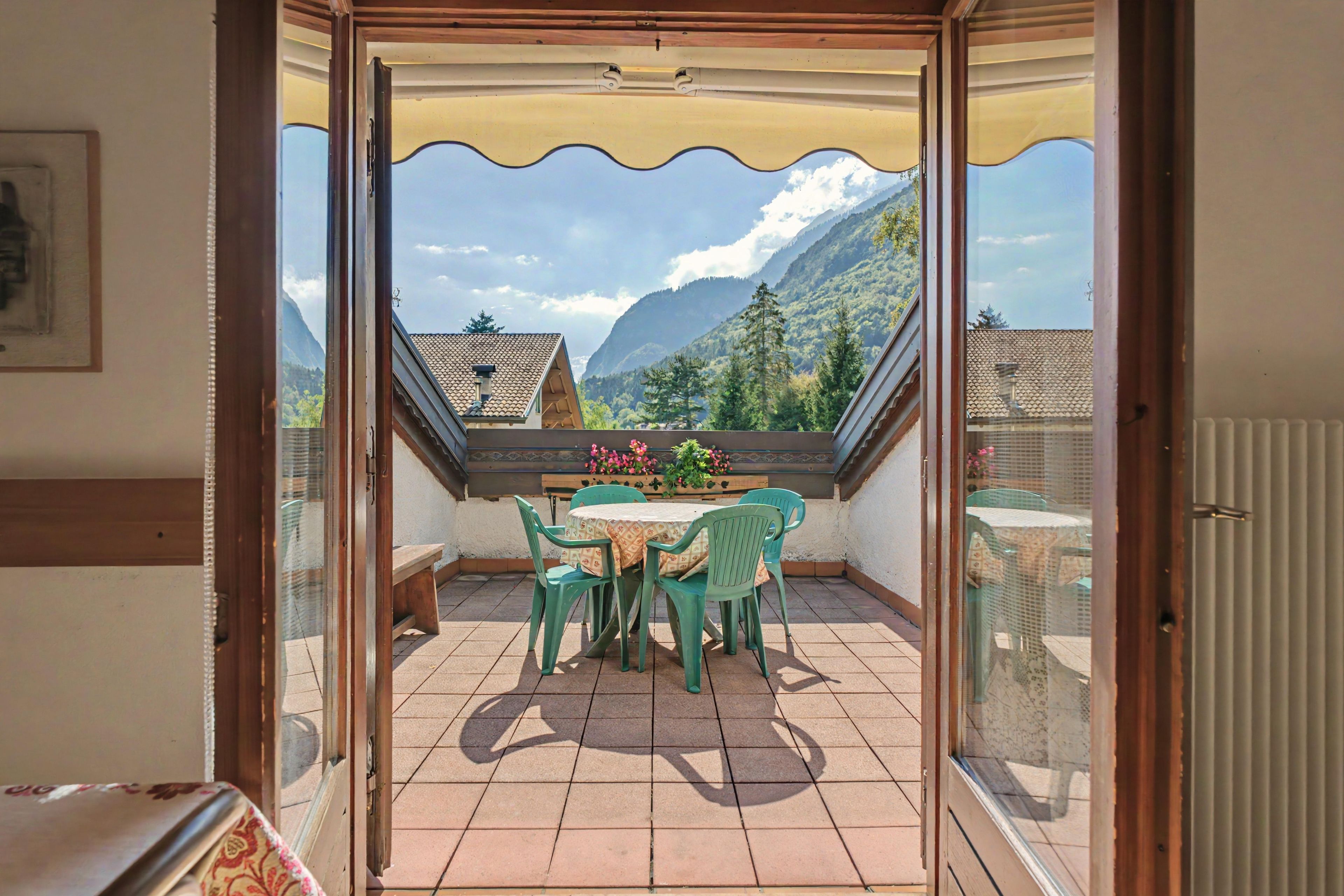 Ein Balkon mit Tisch und Stühlen, Blick auf Berge und einen klaren Himmel.