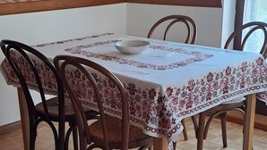 Ruokailutila, jossa on puinen pöytä, tuolit ja kalanruotokuviollinen lattia.