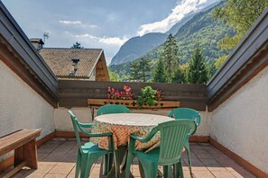 A terrace with a round table and chairs, a wooden bench, and a flower planter. - Apartment 'Bianca' with Lake View, Wi-Fi and Air Conditioning (Molveno)