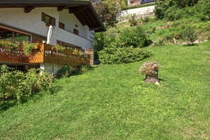 A house with a sloped roof, a wooden balcony with flower boxes, and a well-maintained lawn. - Apartment 'Bianca' with Lake View, Wi-Fi and Air Conditioning (Molveno)