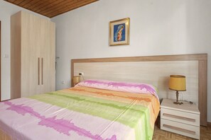 A bedroom with a bed, a nightstand, a lamp, a wardrobe, and a framed picture on the wall. - Apartment 'Bianca' with Lake View, Wi-Fi and Air Conditioning (Molveno)