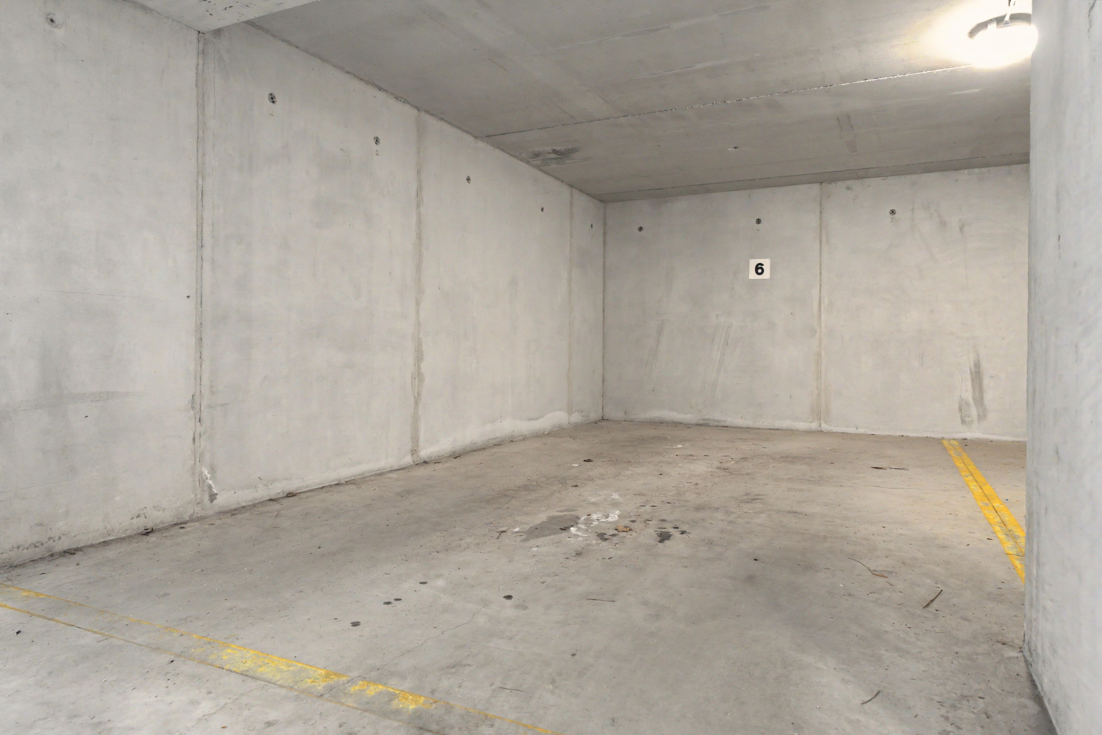 Un estacionamiento vacío con paredes y suelo de hormigón, y el número '6' en una de las paredes.