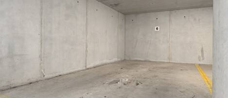 A vacant parking garage with concrete walls, a concrete floor, and a single number '6' on one wall.