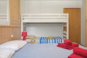 Habitación con literas, una lámpara roja, una toalla enrollada y una puerta.