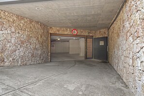Einfahrt zu einer Parkgarage mit Steinmauern, einem Höhenbeschränkungszeichen und einer geschlossenen Garagentür.