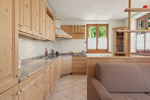 Una cucina con mobili in legno, un piano di lavoro in granito e una finestra con tende.