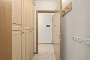 Un corridoio con porte in legno e pavimento piastrellato.