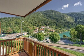 Un balcone con vista su un paesaggio montuoso, una strada con un ponte e un corpo d'acqua.