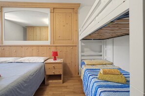 Una camera da letto con un'armadiatura in legno, un comodino con una lampada e un letto a castello.