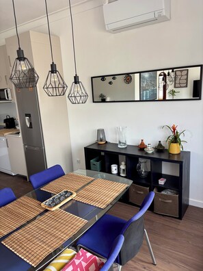 Eine moderne Küche mit Kühlschrank, Mikrowelle und Esstisch mit blauen Stühlen.
