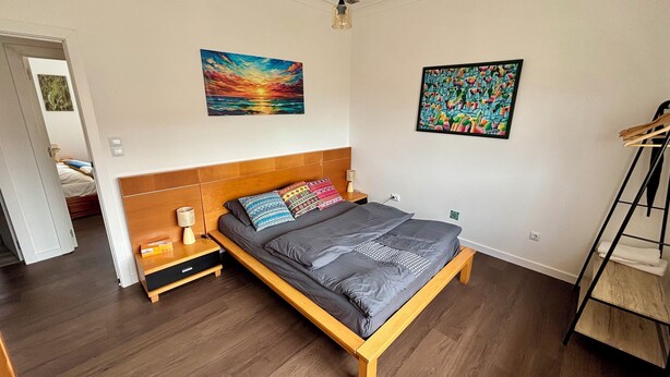 Ein Schlafzimmer mit einem hölzernen Bett, zwei Bildern, einem Nachttisch und einer Leiter.