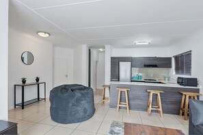 Eine moderne Küche mit Kochinsel, Holzstühlen und einem Sitzsack in einem Wohnbereich.
