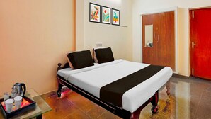 A hotel room with a bed, a ceiling fan, a door, and a wall with three framed pictures.