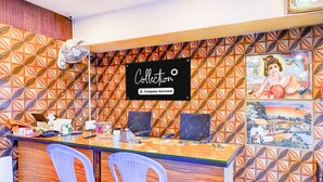A reception desk with a company-serviced sign, two plastic chairs, a fan, and a decorative wall with geometric patterns.