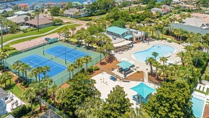 Oversigtsbillede af et resort med tennisbane, swimmingpool og strand.