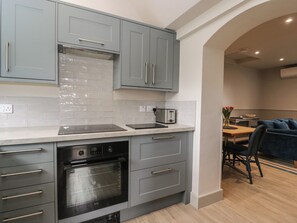 A modern kitchen with grey cabinets, a built-in oven, and a toaster. - Foxglove (Bicester)