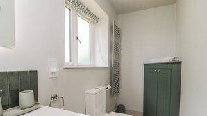 Ein Badezimmer mit Toilette, Waschbecken, Spiegel, Fenster und Schrank.