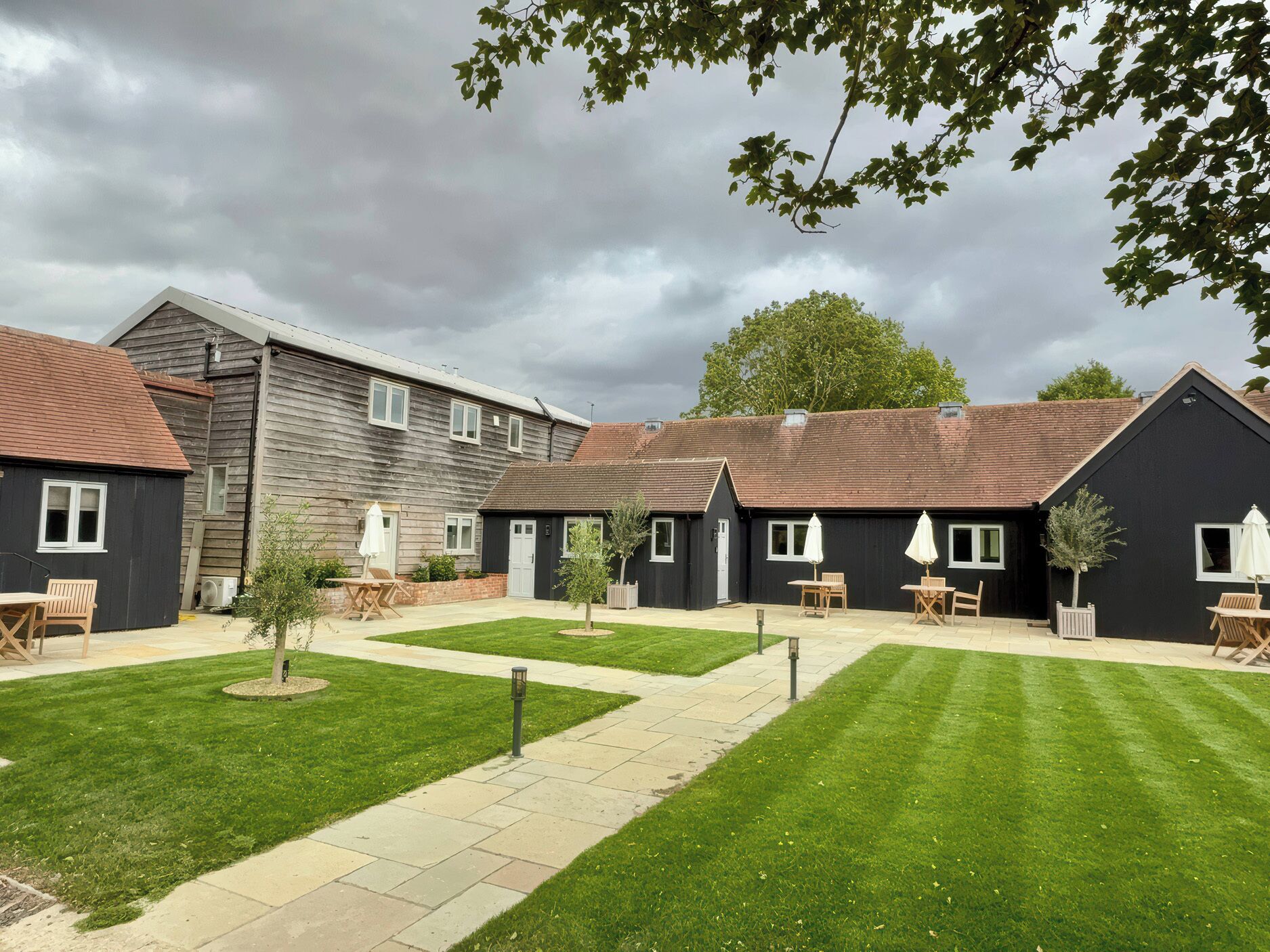 A courtyard with a lawn, outdoor seating, and a building with a dark facade.
