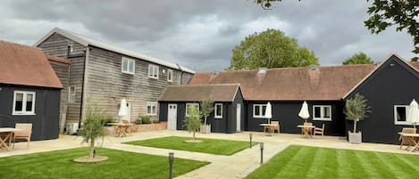 A courtyard with a lawn, outdoor seating, and a building with a dark facade.