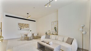 A modern living room with a sofa, coffee table, and dining area. - Elegant 3BR Stay in JVC near Circle Mall (دبي)