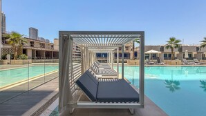 A pool area with a sun lounger, clear pool water, and a view of surrounding buildings. - Elegant 3BR Stay in JVC near Circle Mall (دبي)