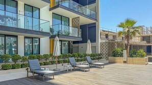 A modern building with a rooftop patio featuring lounge chairs and umbrellas. - Elegant 3BR Stay in JVC near Circle Mall (دبي)