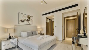 A modern hotel room with a large bed, bedside tables, a desk, and a mirror. - Elegant 3BR Stay in JVC near Circle Mall (دبي)