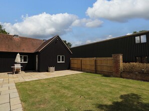 A residential property with a paved patio, a wooden fence, and a grassy yard. - Poppy Patch (Bicester)