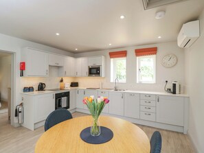 Una cocina moderna con armarios blancos, microondas, lavabo y un comedor con una mesa redonda y sillas.