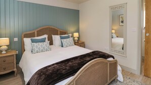 A bedroom with a bed, bedside tables, a mirror, and a door. - Poppy Patch (Bicester)