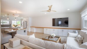 A modern living room with a sofa, coffee table, and a television mounted on the wall. - Charming Encinitas Retreat Near Local Beaches (Encinitas)