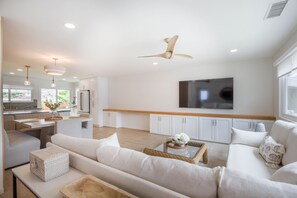 A modern living room with a sofa, coffee table, and a television mounted on the wall. - Charming Encinitas Retreat Near Local Beaches (Encinitas)