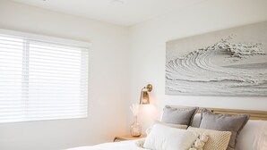 A bedroom with a bed, a nightstand, a wall-mounted lamp, and a painting. - Charming Encinitas Retreat Near Local Beaches (Encinitas)