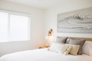 A bedroom with a bed, a nightstand, a wall-mounted lamp, and a painting. - Charming Encinitas Retreat Near Local Beaches (Encinitas)