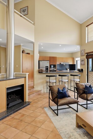 A modern kitchen with a central island, bar stools, and a fireplace. - Spacious, sun-drenched 5-bedroom home in prime Applecross. Featuring a private pool, indoor pool table, secure outdoor spaces, and high ceilings, this retreat is designed for unforgettable family memories by the river. (Applecross)