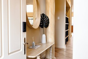 An interior hallway with a wooden bench, a large mirror, a black decorative leaf, and a white vase with a plant. - Spacious, sun-drenched 5-bedroom home in prime Applecross. Featuring a private pool, indoor pool table, secure outdoor spaces, and high ceilings, this retreat is designed for unforgettable family memories by the river. (Applecross)