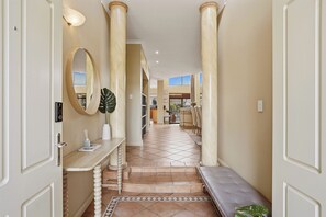 A hallway with a bench, a mirror, and a potted plant. - Spacious, sun-drenched 5-bedroom home in prime Applecross. Featuring a private pool, indoor pool table, secure outdoor spaces, and high ceilings, this retreat is designed for unforgettable family memories by the river. (Applecross)