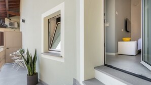 Un intérieur moderne avec un escalier, une plante en pot, un téléviseur et un petit coin salon.