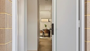 Un corridoio con un tappeto che conduce a una porta, un paio di scarpe sul tappeto e una zona pranzo sullo sfondo.