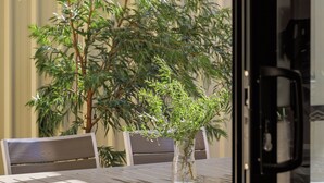 Una veranda con tavolo e sedie, una pianta in vaso e una porta scorrevole in vetro.