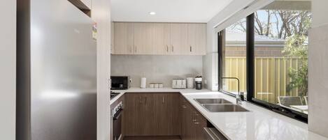 A modern kitchen with a refrigerator, microwave, toaster, and sink.