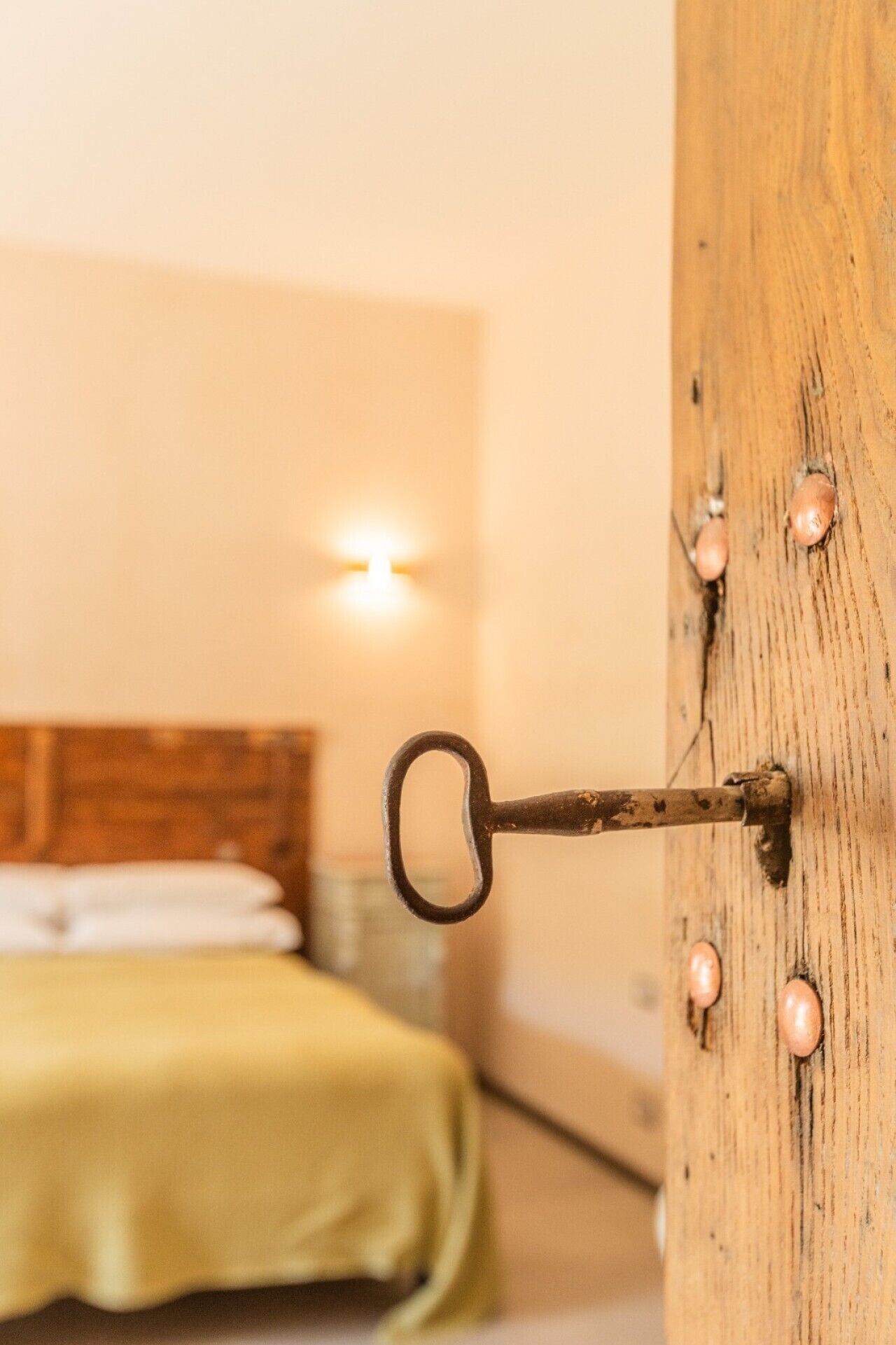 Une clé dans une porte en bois, avec un lit en arrière-plan.