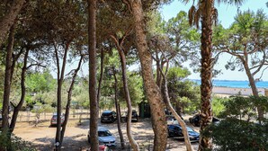 A parking area with cars, trees, and a view of the sea. - Tamarè 3 by Casa di Marco (Conchiglie-Alto Lido)