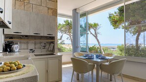 A modern kitchen with a view of the sea, a dining area with chairs, and a table set for two. - Tamarè 3 by Casa di Marco (Conchiglie-Alto Lido)