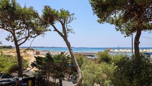 A coastal view with trees, a beach, and a distant cityscape. - Tamarè 3 by Casa di Marco (Conchiglie-Alto Lido)