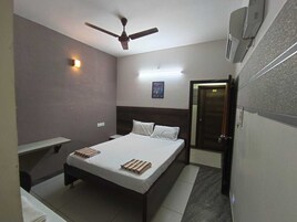 A bedroom with a bed, a ceiling fan, a nightstand, a bedside table, and a door.