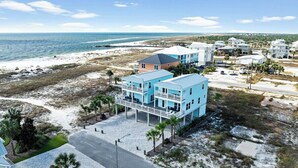 A coastal hotel with a light blue exterior, multiple floors, and a balcony overlooking the beach. - Mariner 1: BeachFront Cottage A, Gulf Front Views! (Mexico Beach)