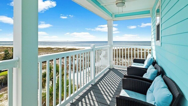 A covered porch with a view of the beach, white railings, and wicker furniture. - Mariner 1: BeachFront Cottage A, Gulf Front Views! (Mexico Beach)