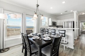 A modern kitchen with white cabinetry, a central island, and a dining area with a table set for four.